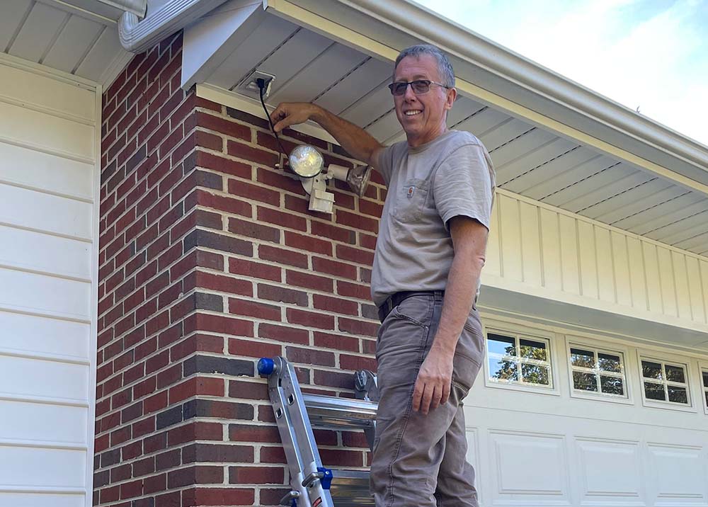 Tom, one of our home inspectors, on a ladder preforming a home inspection 